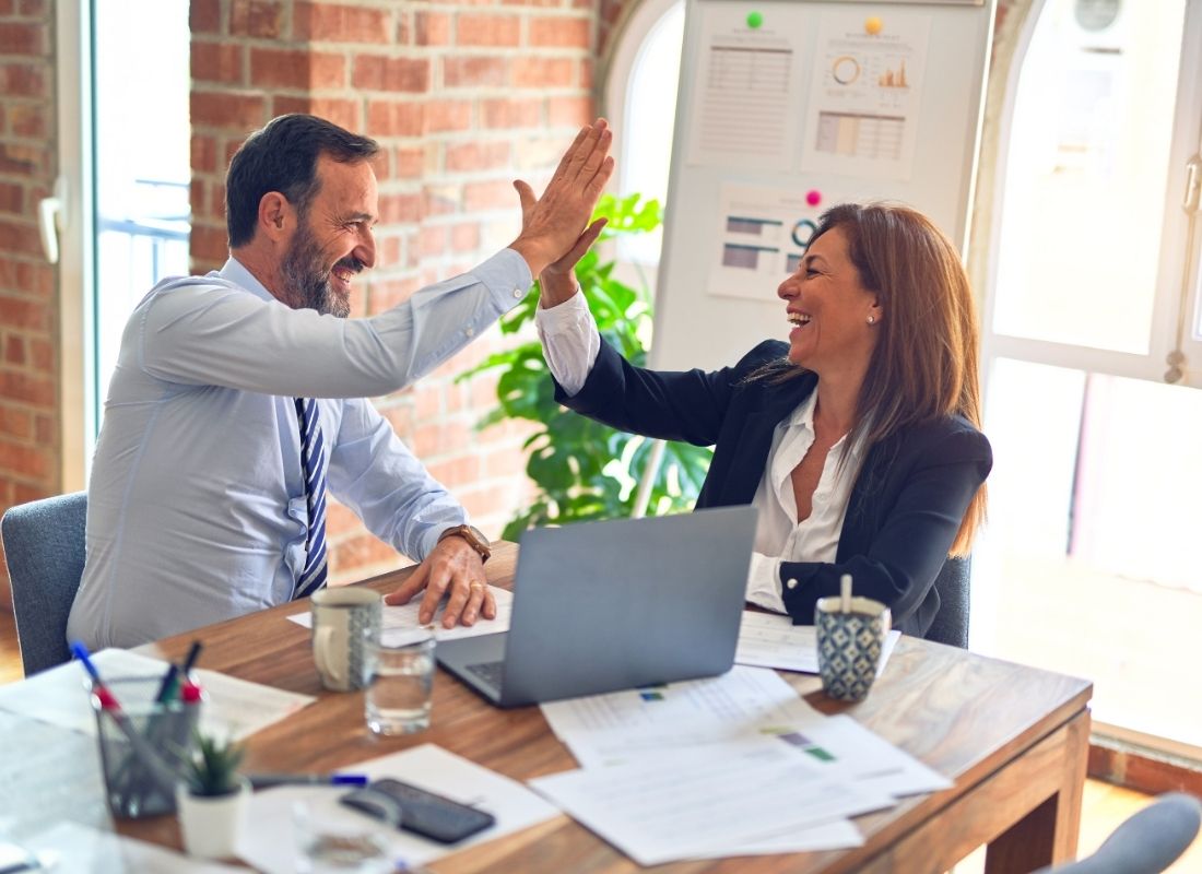 Two confident coworkers high five at work