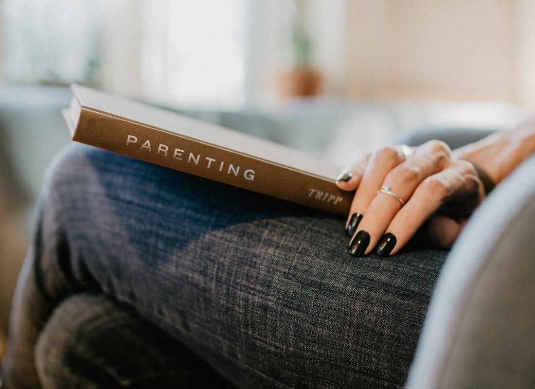 Parent with parenting book in lap