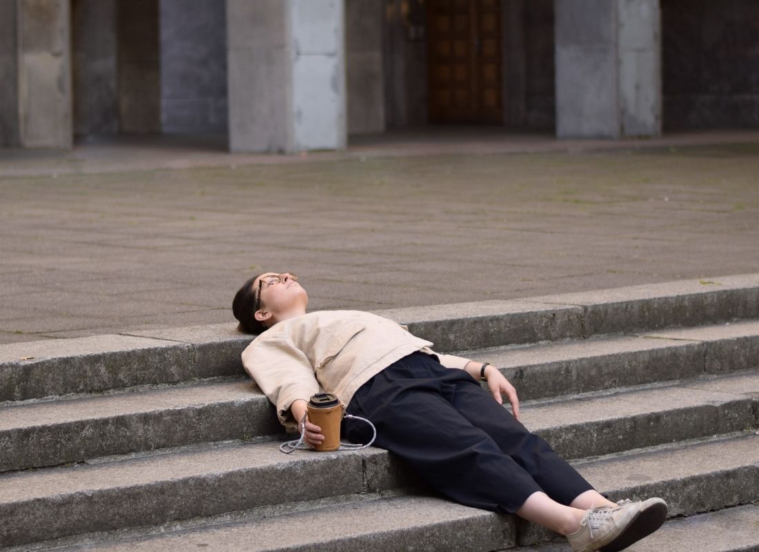 Tired person laying on staircase with coffee cup