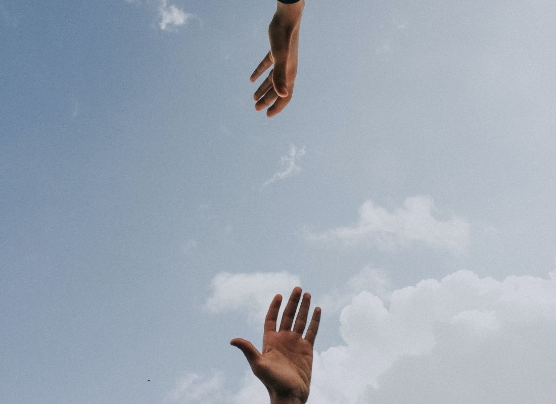 blue sky with two hands reaching for each other