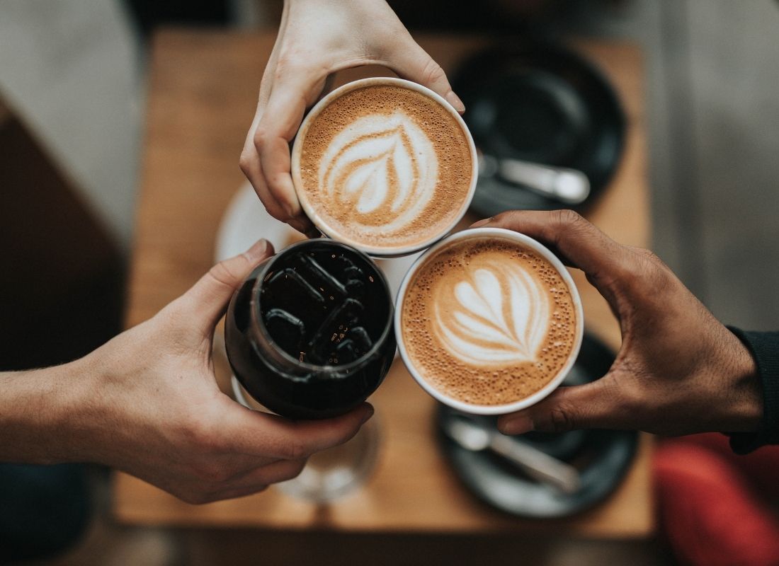 three hands holding three lattes