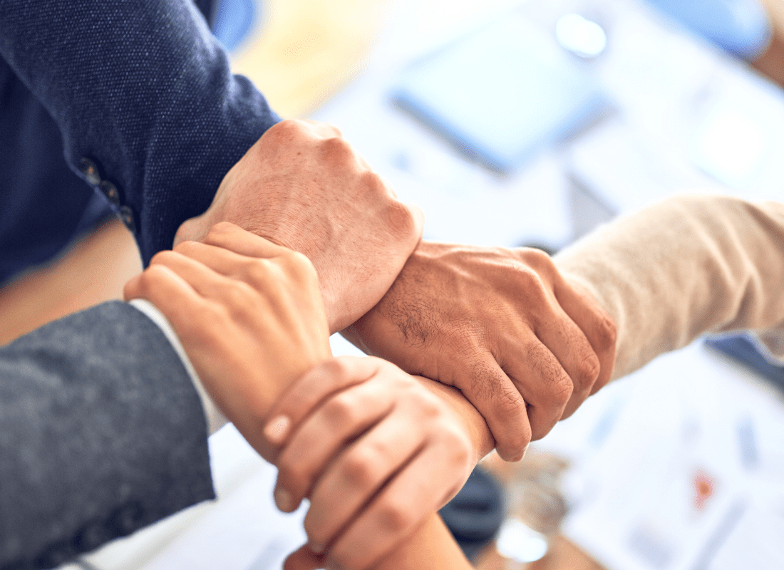 Four company team members holding each others wrists in solidarity