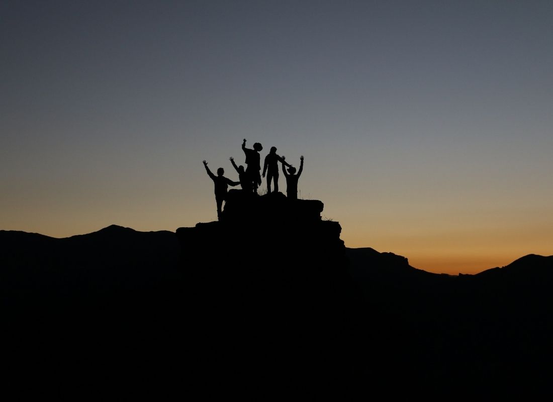 Successful team of hikers on top of a mountain at dusk