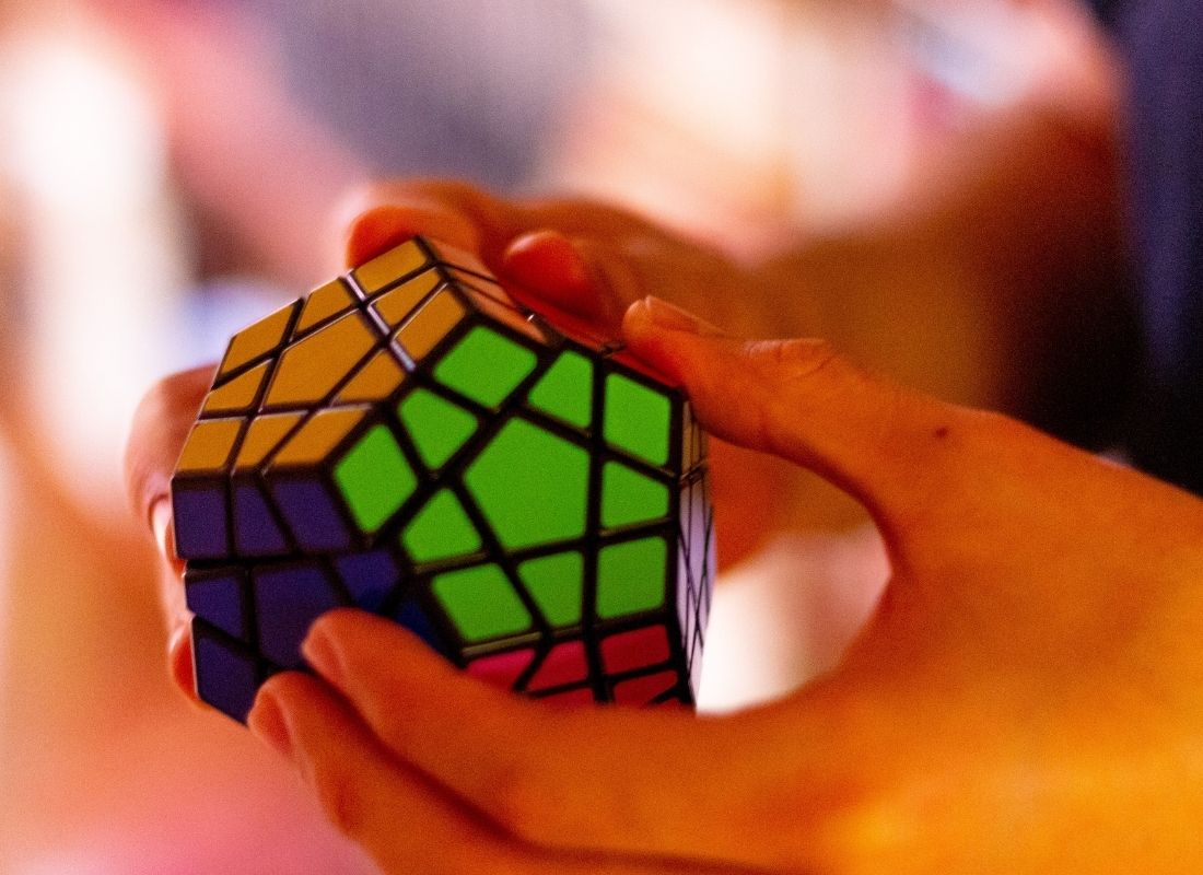 Person holding hexagonal colored Rubix cube and solving puzzle