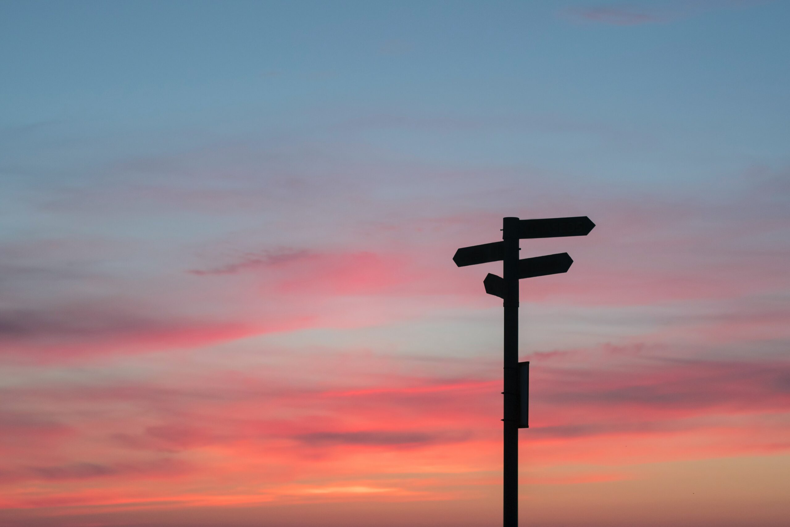 Image of a signpost silhouette on a pink and yellow sunset background